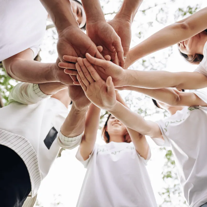 Many hands stacked together in a circle as a sign of shared commitment