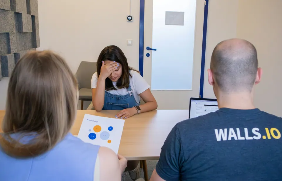 Two advisers at a desk with a woman holding her head over a financial chart during a money consultation
