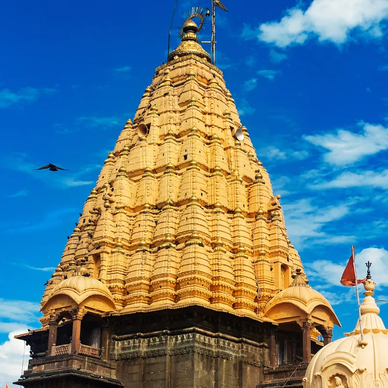 The golden spire of a Hindu temple in Ujjain against a blue sky