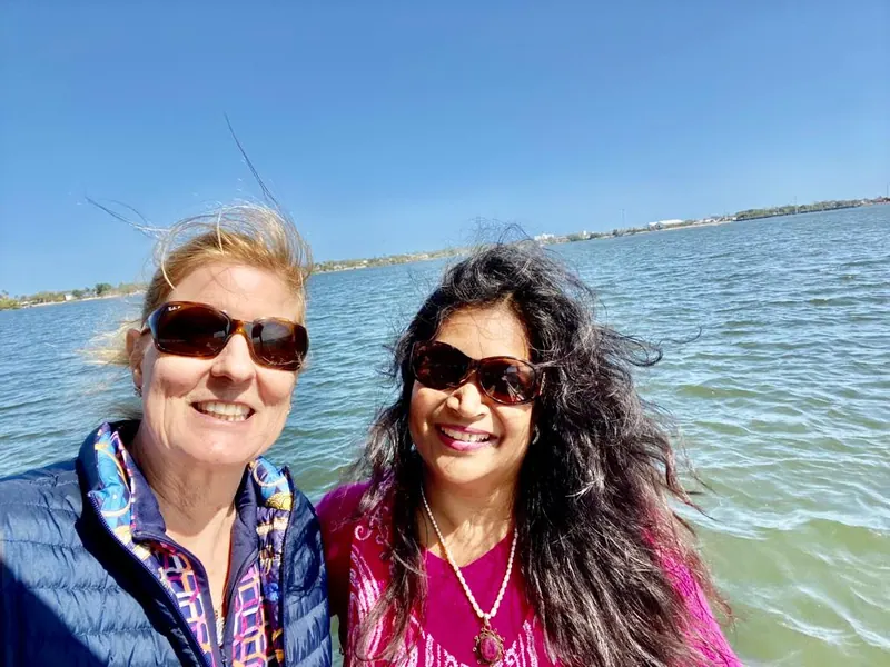 Two women in sunglasses standing beside the water