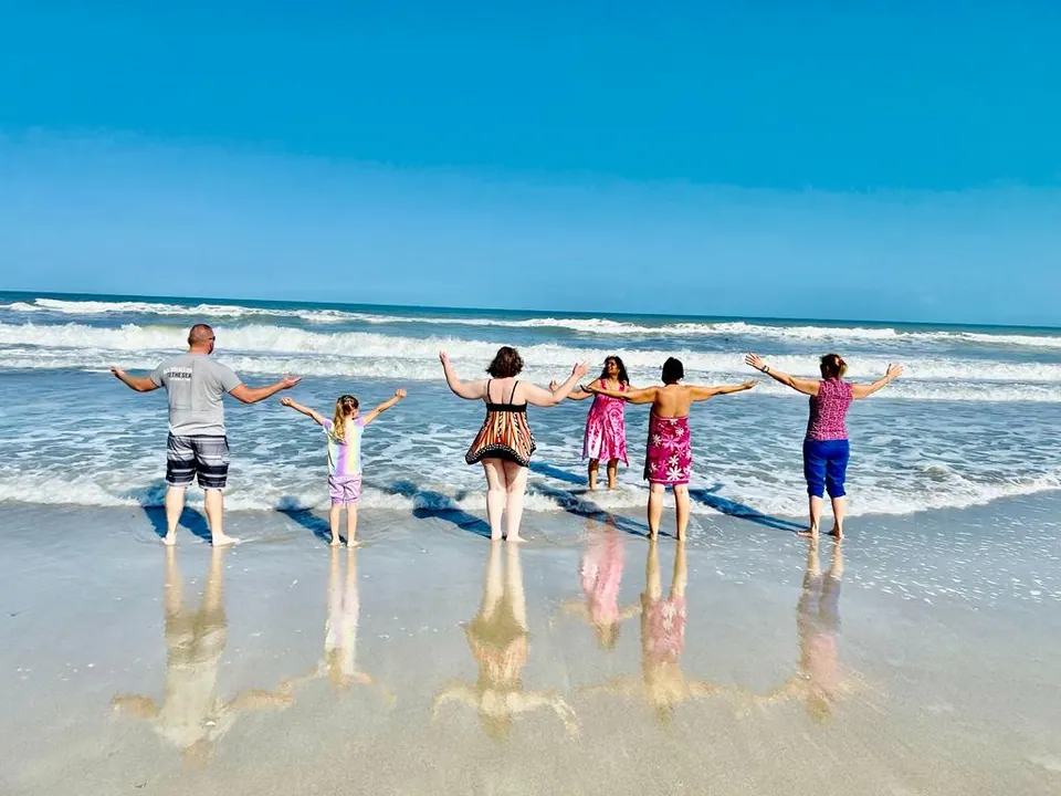 Five people standing hand in hand in shallow sea water