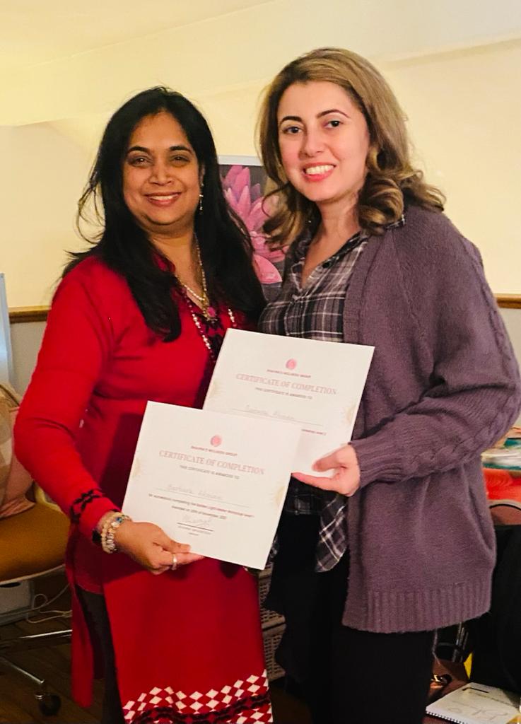 Bhavna Srivastava presenting a certificate of completion to a graduate in a purple sweater