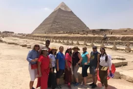 Smiling individuals posing in front of the Pyramid of Egypt