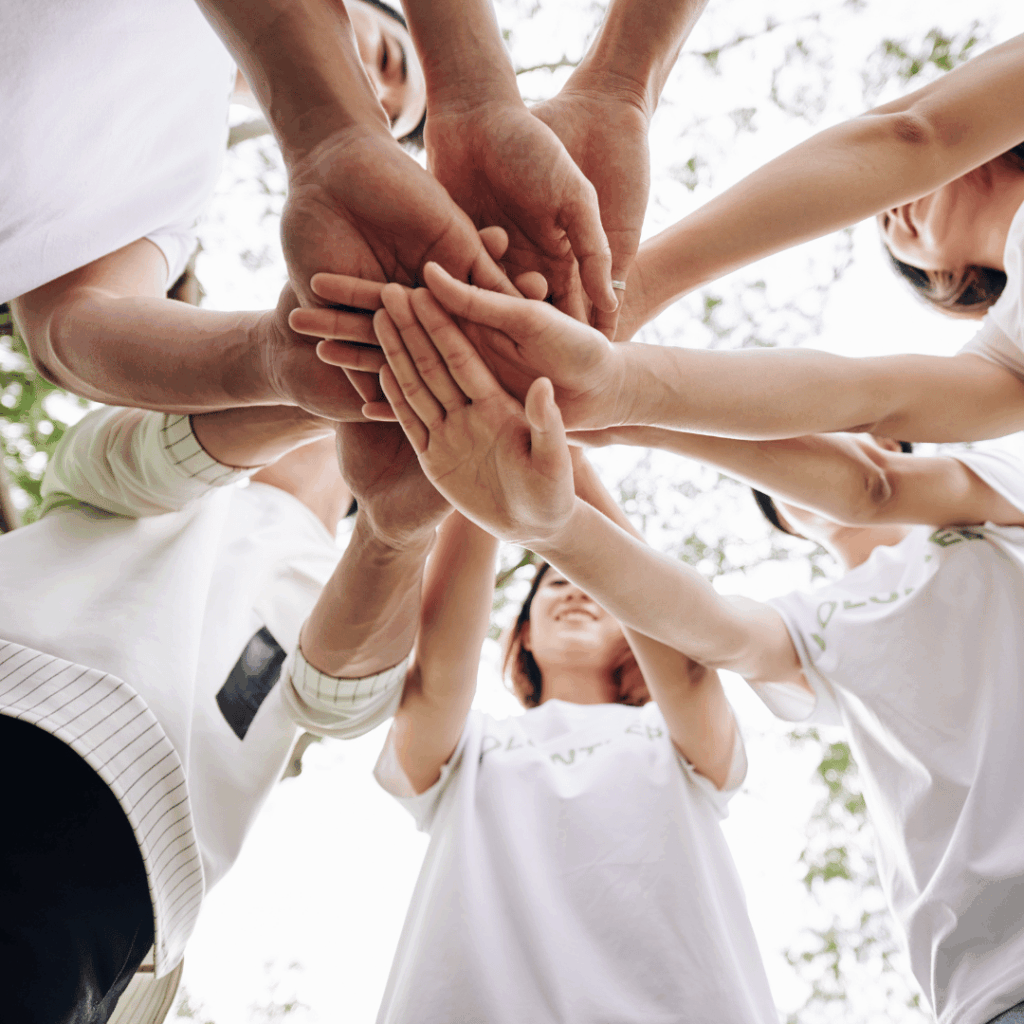 Many hands stacked together in a circle as a sign of shared commitment