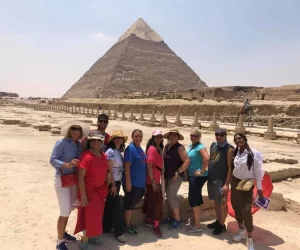 Smiling individuals posing in front of the Pyramid of Egypt