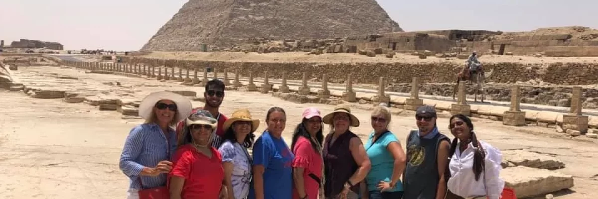 Smiling individuals posing in front of the Pyramid of Egypt